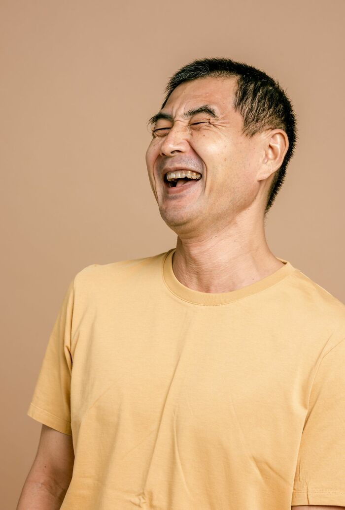 A man with closed eyes laughing heartily, representing phrases that crack people up.