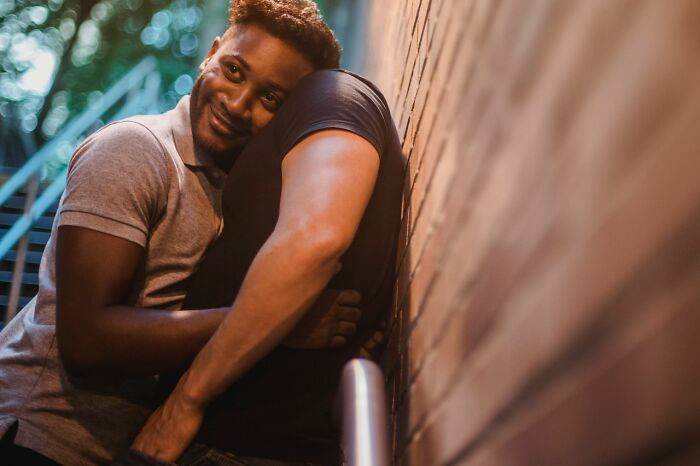 A smiling man hugging another person, showing a moment of connection amidst challenging public horror stories.