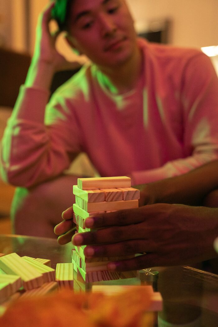 Hands play a Jenga game on a table, with a blurred person in the background. This shows women changing their minds.