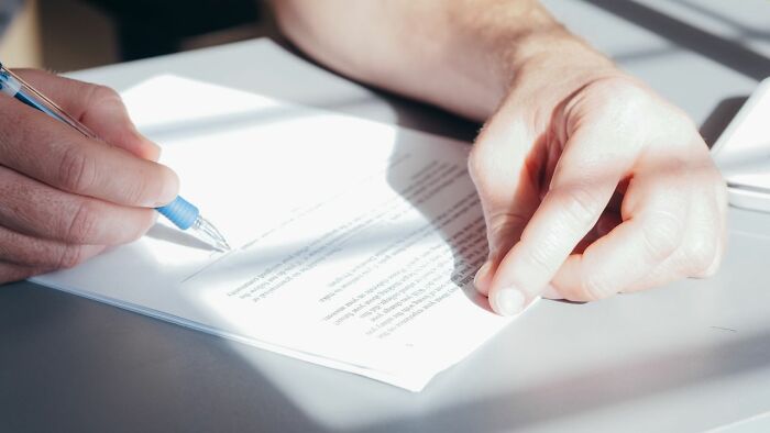 Man signing documents, revealing behind the scenes secrets companies dont want you to know.