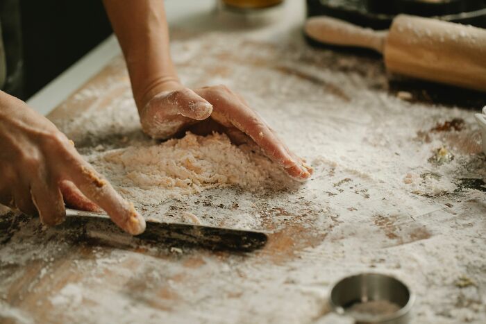 Hands mixing flour on a wooden surface, showing places that failed health inspections.