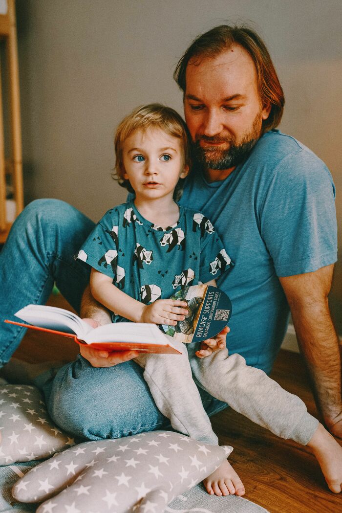 A father reads to his child on the floor, illustrating unexpected twists and turns that changed people's lives.