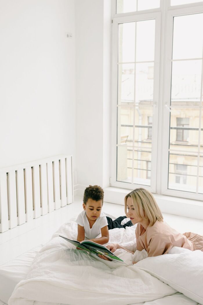 A woman and a child reading a book on a bed, sharing quiet moments that reveal behind the scenes secrets companies don't want you to know.