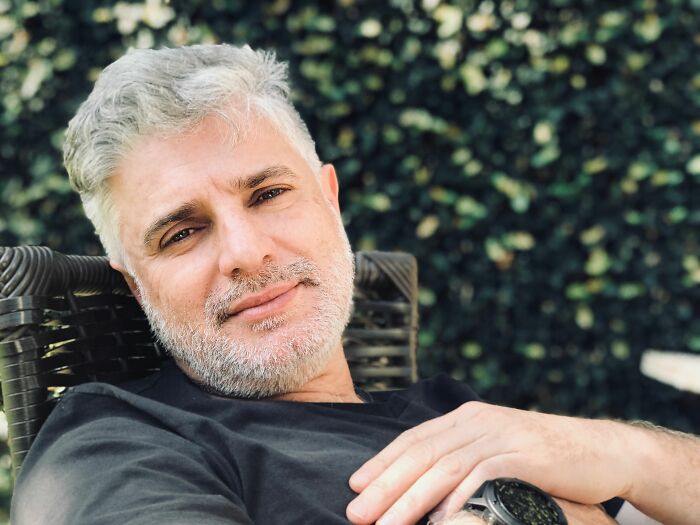 A smiling man with gray hair and a beard sits outdoors, enjoying a moment of calm amidst life changes.