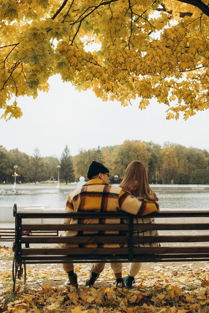 A couple sits on a bench by a lake in autumn, symbolizing unexpected twists and turns that changed their lives.