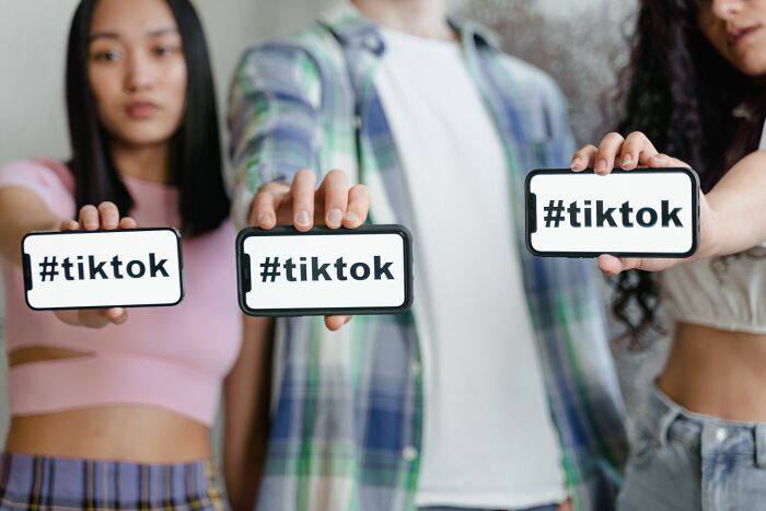 Three young people holding phones displaying the #tiktok hashtag, representing TikTok and Gen Z internet slang culture. Three young people holding phones displaying the #tiktok hashtag, representing TikTok and Gen Z internet slang culture.