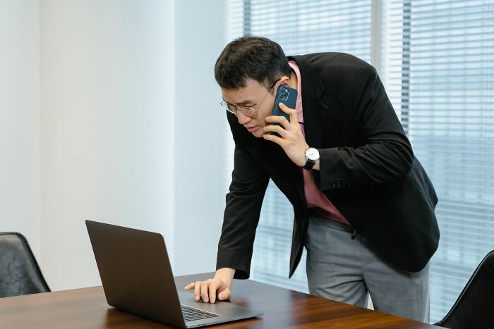 A man talking on the phone while looking at a laptop, revealing industry secrets of modern work jobs.