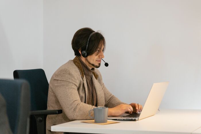 A man with a headset and laptop at a desk, revealing industry secrets about jobs.