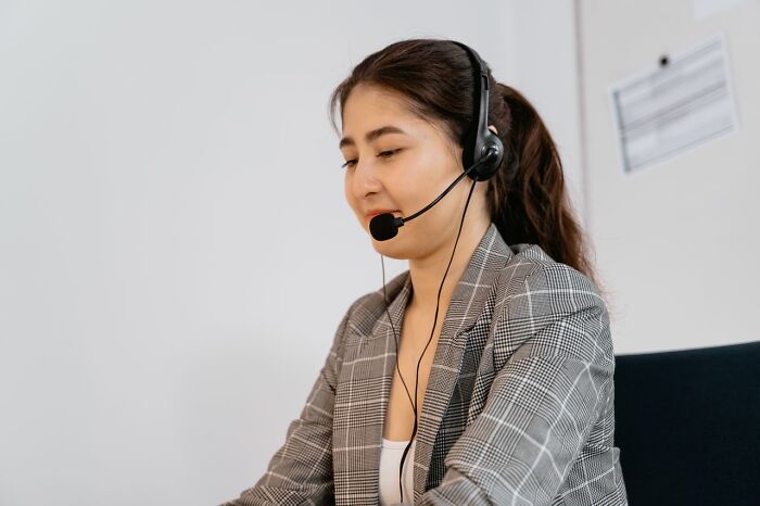 A woman wearing a headset, smiling and working at a desk, revealing behind the scenes secrets companies don't want you to know.