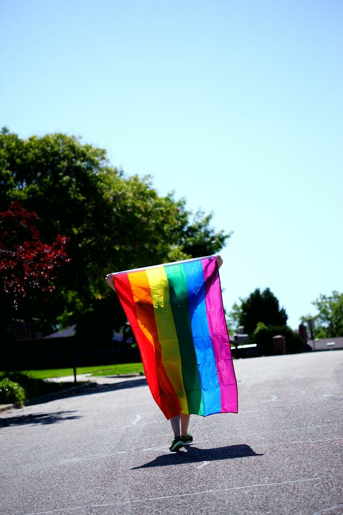 A person holding a rainbow flag, symbolizing diversity in the workplace and HR problems.