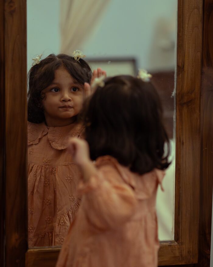 A young child looking at their reflection in a mirror, a scene that might make parents terrified.