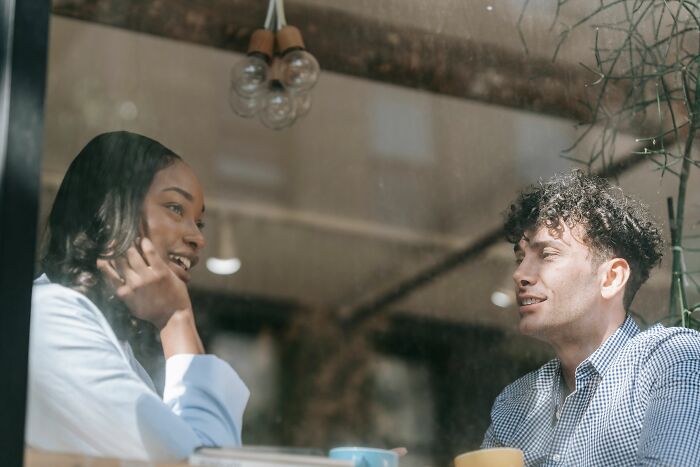 A smiling woman and a man in a coffee shop, showcasing dynamics of why women changed their minds about 'perfect' guys.