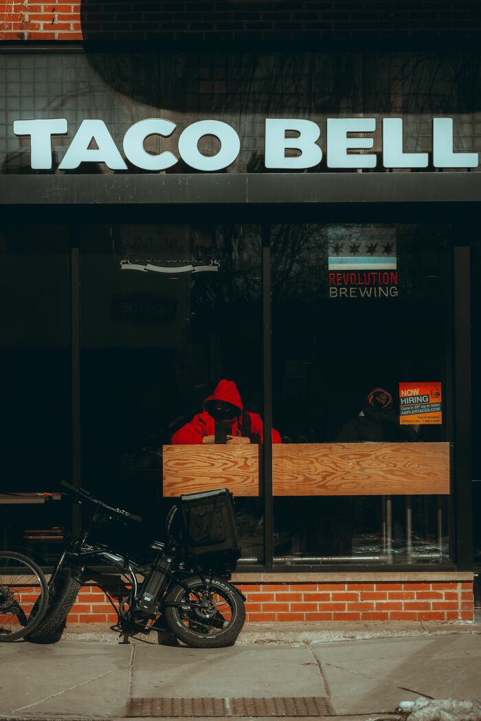 Exterior of a Taco Bell with a person in a red hoodie inside, related to health inspections and vegetarian options.