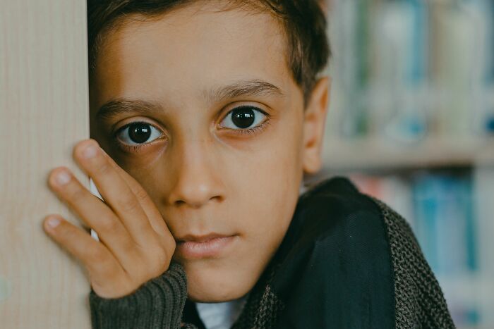 A young boy with wide eyes, looking directly at the camera, conveying the feeling when parents were terrified of their children.