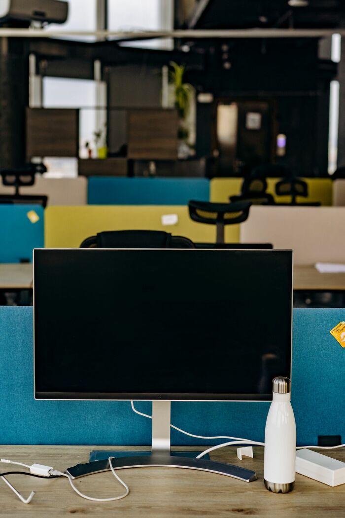 An empty office cubicle with a monitor, representing environments where entitled friends may interact.