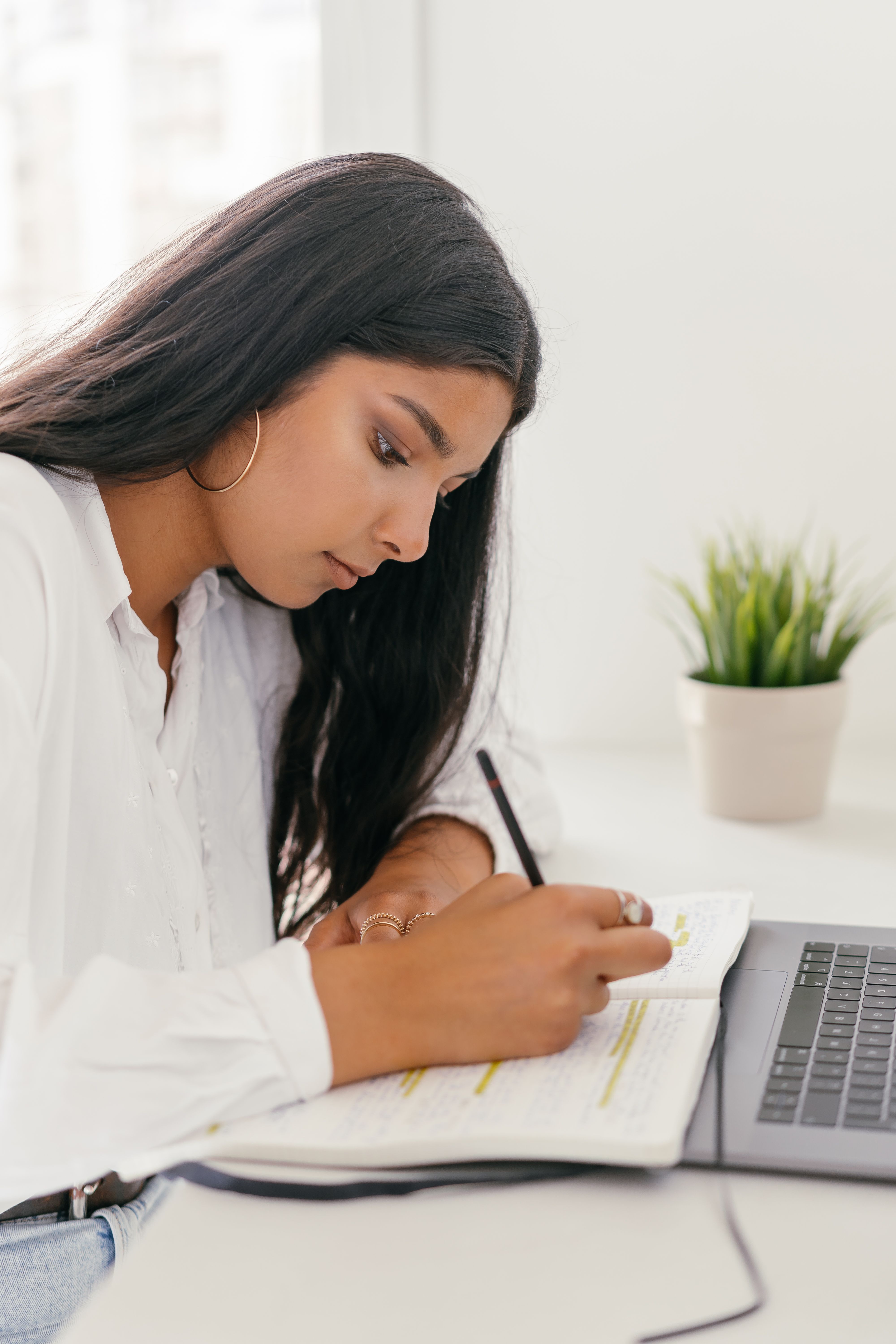 A teenage girl studies intently at a desk, writing in a notebook, focused on her work despite sexist remarks. A teenage girl studies intently at a desk, writing in a notebook, focused on her work despite sexist remarks.
