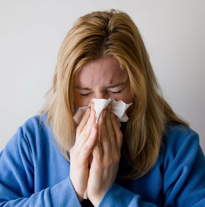 A woman blowing her nose with a tissue, symbolizing public horror stories and feeling unwell.