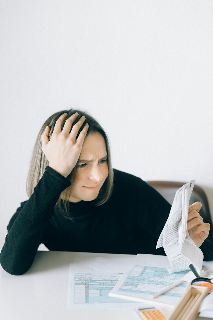A woman looks frustrated while reviewing documents, revealing behind the scenes secrets companies don't want you to know.