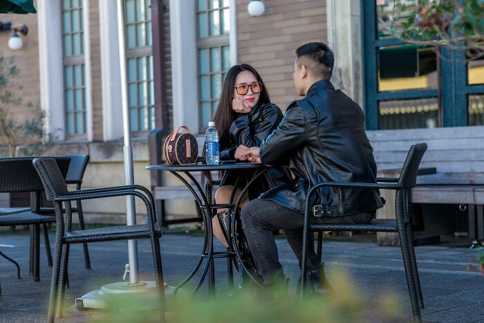 A couple sits at an outdoor cafe. The woman looks intently at the man. This shows women changing their minds.