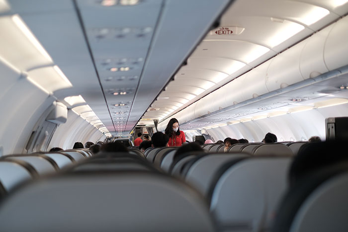 An aisle view inside an overnight flight with passengers and a flight attendant, highlighting a reclining incident.
