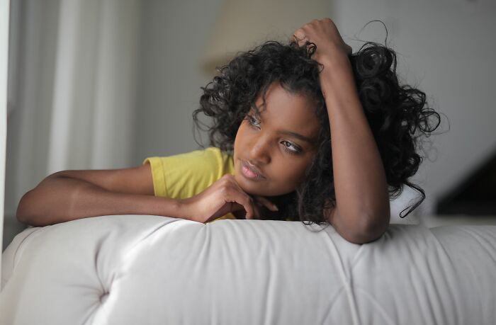 A young woman with curly hair looks thoughtful, reflecting on a guy she once thought was perfect and his baby talk.