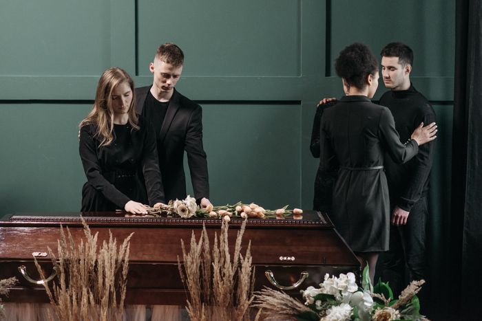 Mourners dressed in black at a funeral service, standing around a wooden casket, reflecting on an entitled aunt's actions. Mourners dressed in black at a funeral service, standing around a wooden casket, reflecting on an entitled aunt's actions.