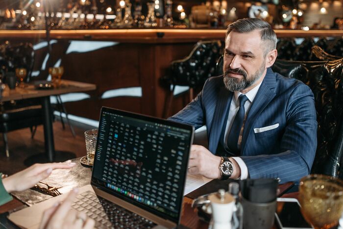 Two professionals discussing data on a laptop in a restaurant, revealing industry secrets about their jobs.