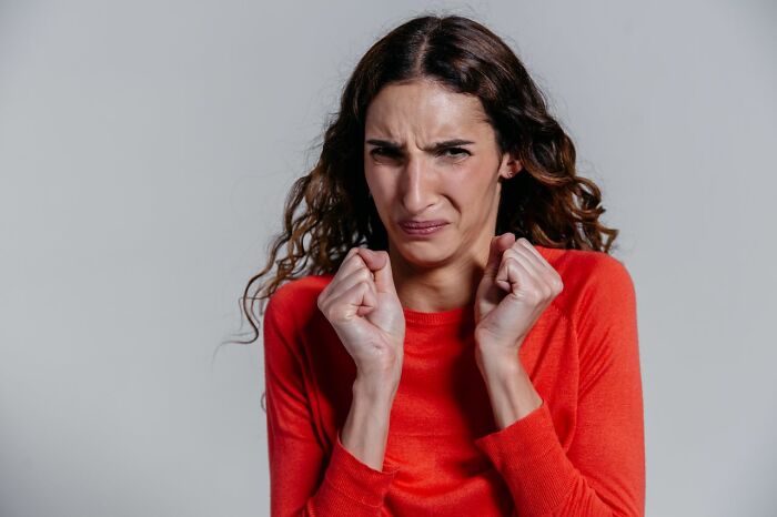 A woman making a disgusted face, clenching her fists, representing HR dealing with ridiculous problems.