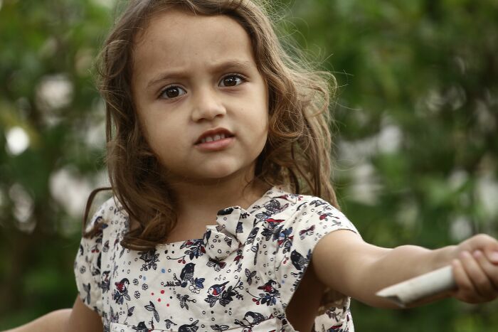 A young girl with long brown hair looks curious, perhaps realizing every family has its own version of normal.