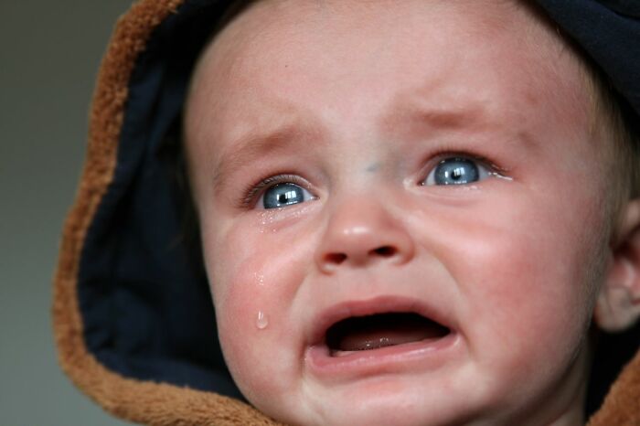 A crying baby in a hooded top, illustrating public horror stories and challenges.