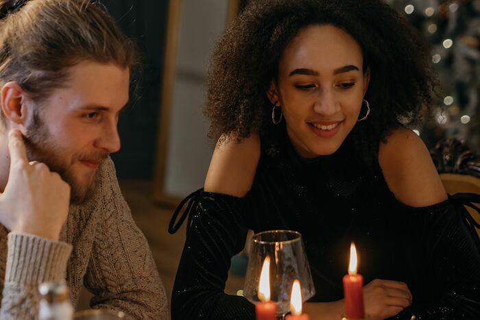 A man with a beard and a woman with curly hair sit at a table with candles. This shows women changing their minds.