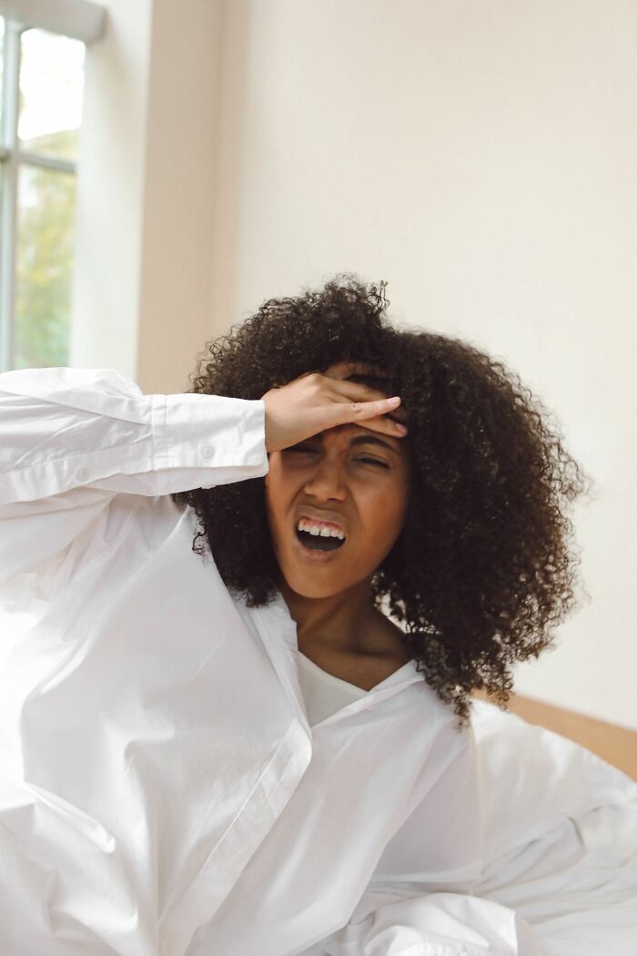 A woman with curly hair looking shocked, covering her forehead. This image depicts unusual ways people have lost their lives.