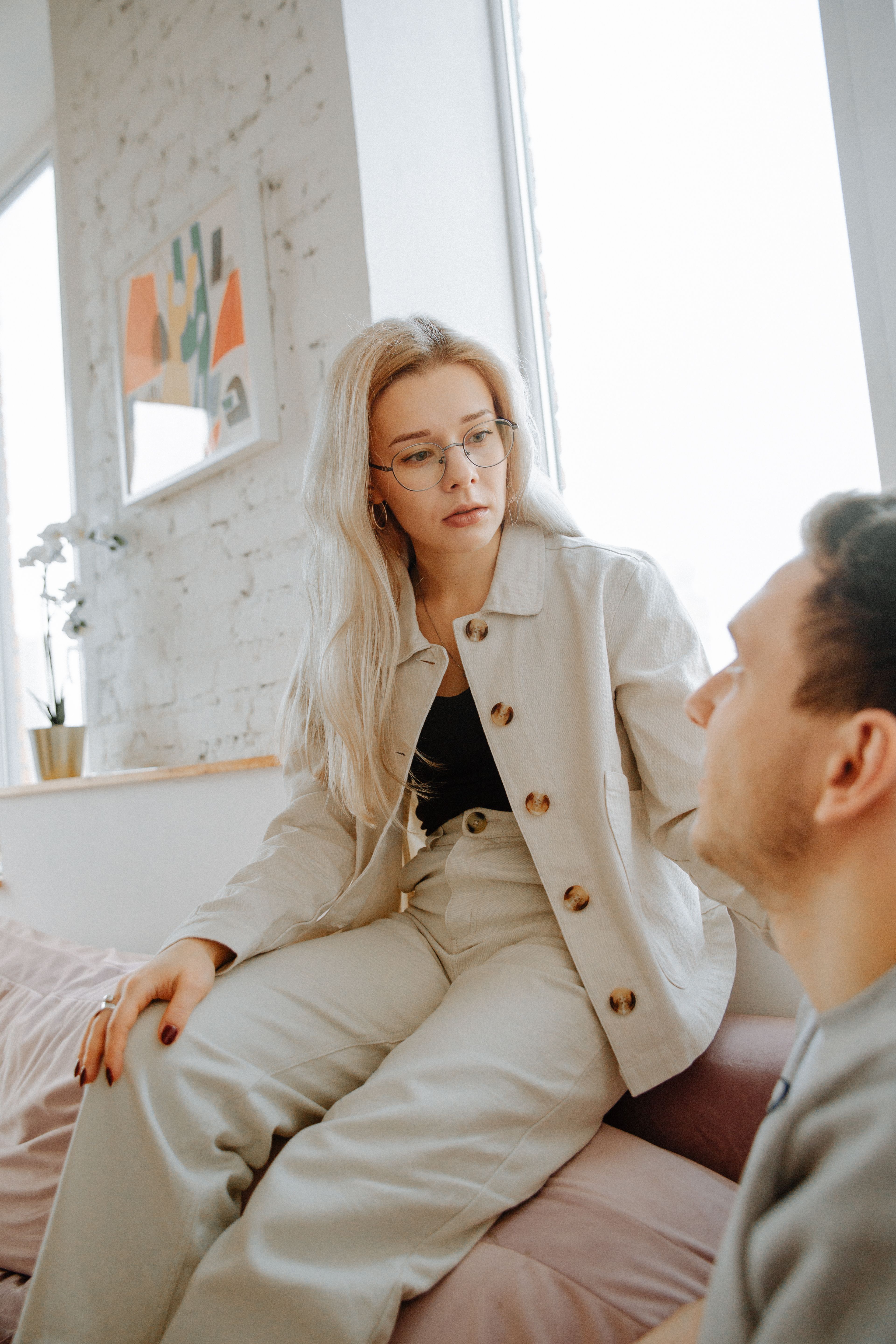Wife's reaction: A woman in glasses and a light jacket sits facing a man, looking suspicious.