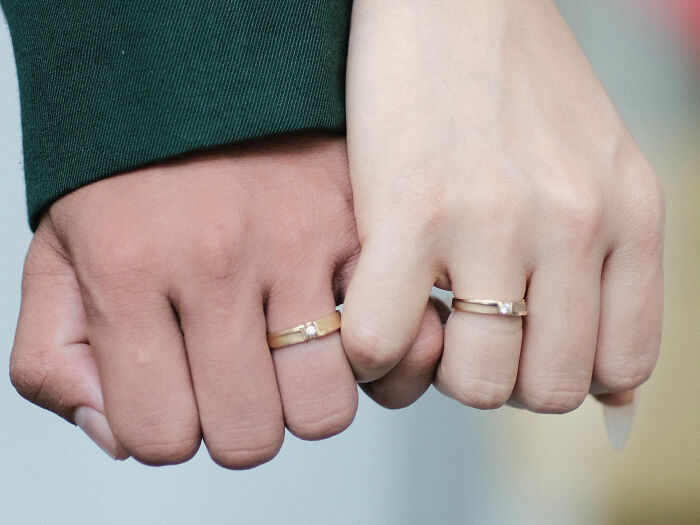 Two hands with wedding rings interlocked, symbolizing the enduring love and extraordinary stories of World War II veterans.