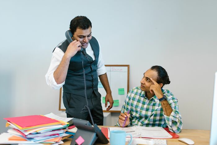 Two men in an office, one on the phone, perhaps discussing a crazy office story from a final day at work.