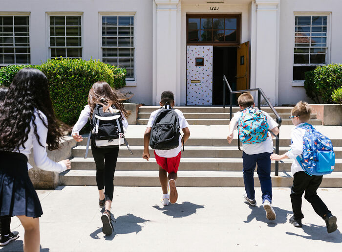 New Jersey middle school students run up the steps of the school building, likely after a yearbook recall and investigation.