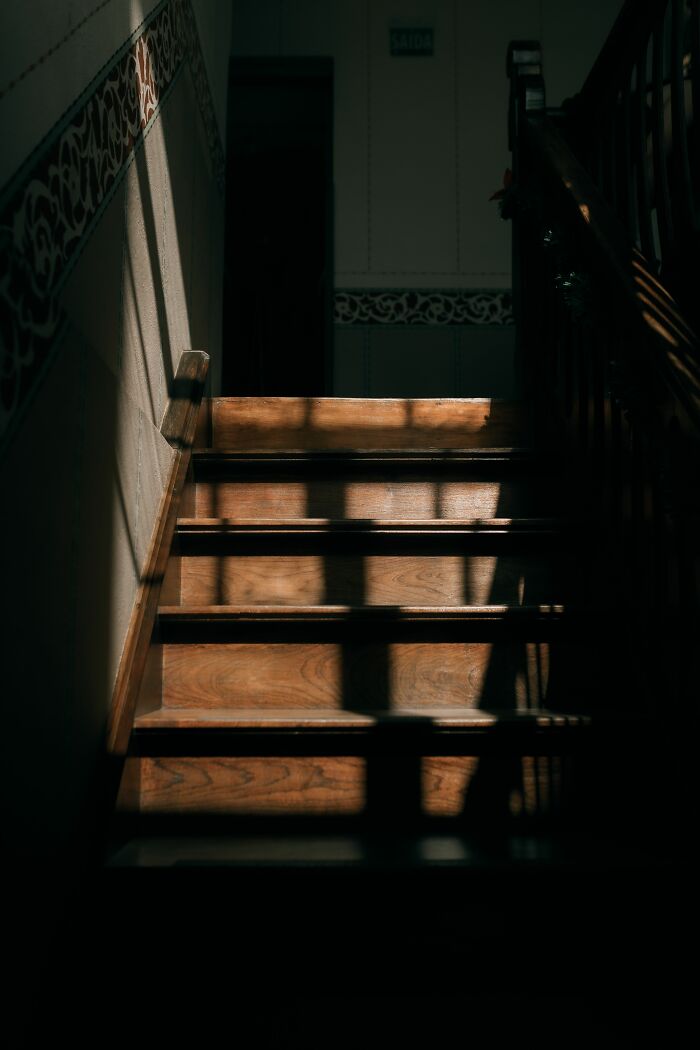 Sunlight casts long shadows on a wooden staircase, creating a spooky atmosphere as parents were terrified.