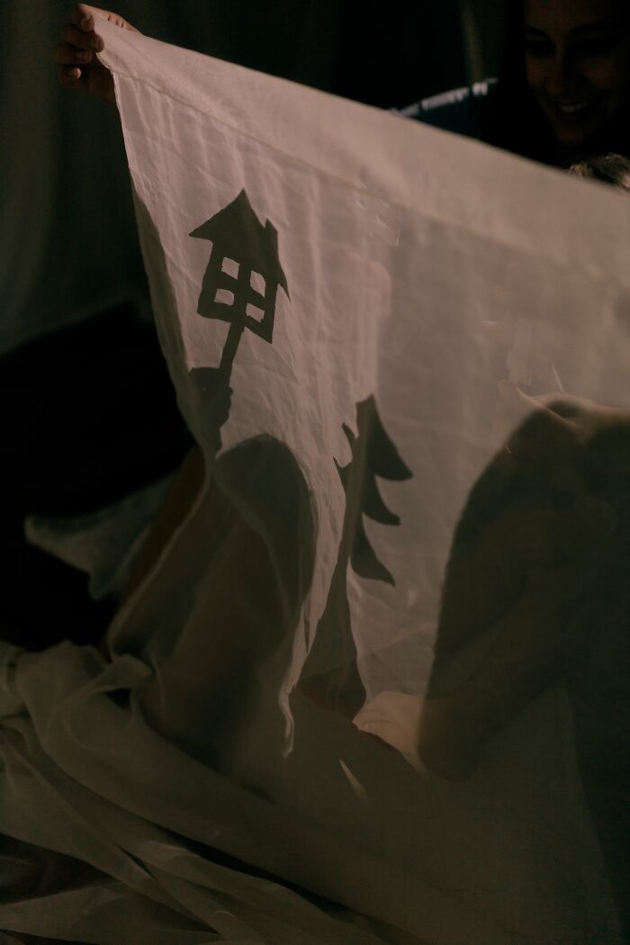 A person holding up a translucent sheet with shadowy figures, creating a sense of being terrified of their own children.
