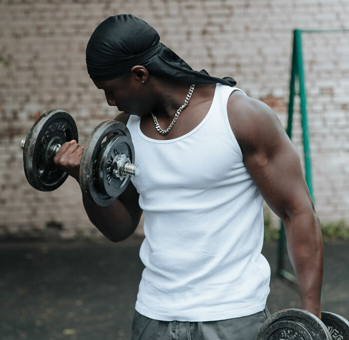 A lonely man working out with dumbbells, showing strength and determination. A lonely man working out with dumbbells, showing strength and determination.