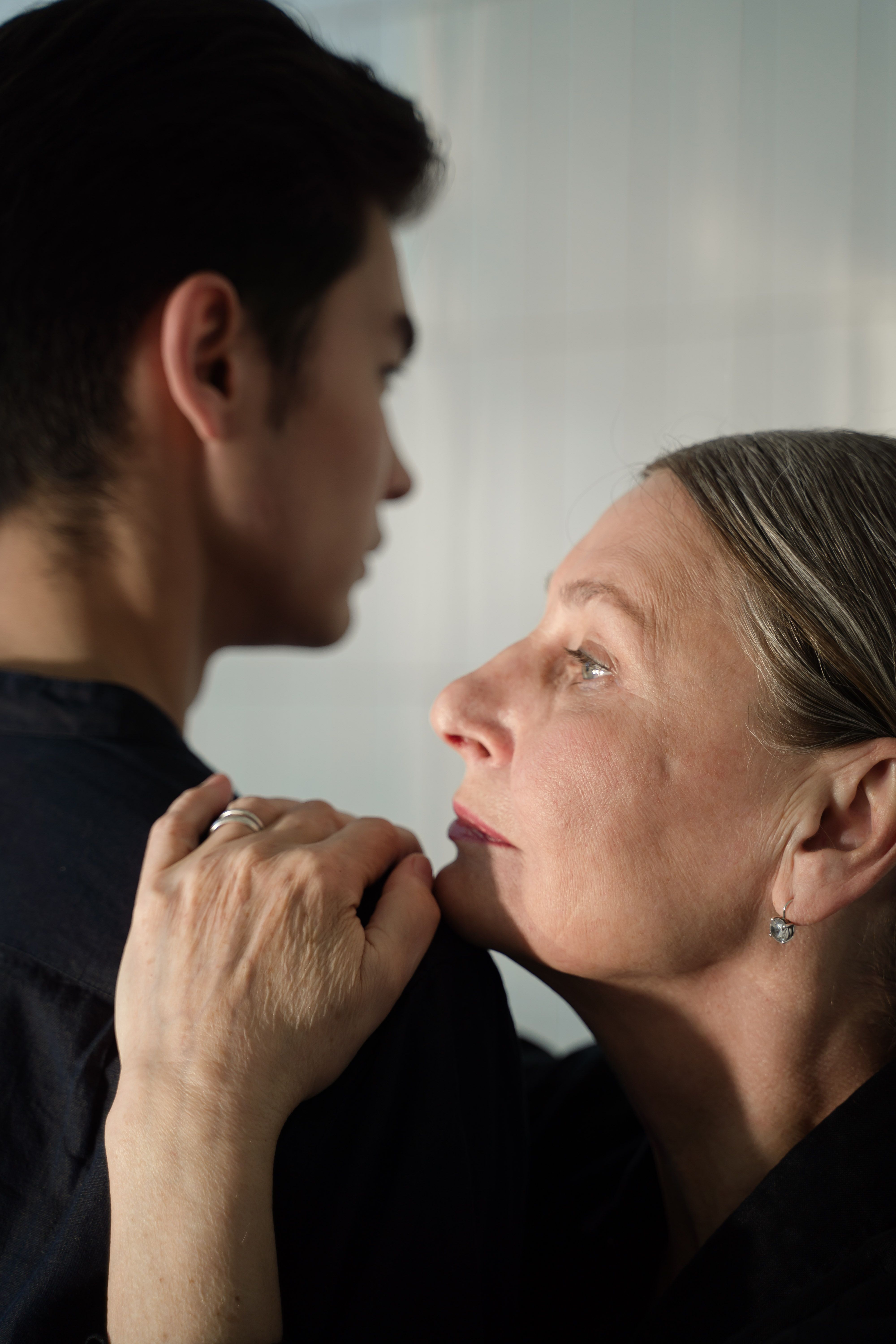 A woman is obsessed with tracking her son's location, gazing at him with concern as she defends her actions.