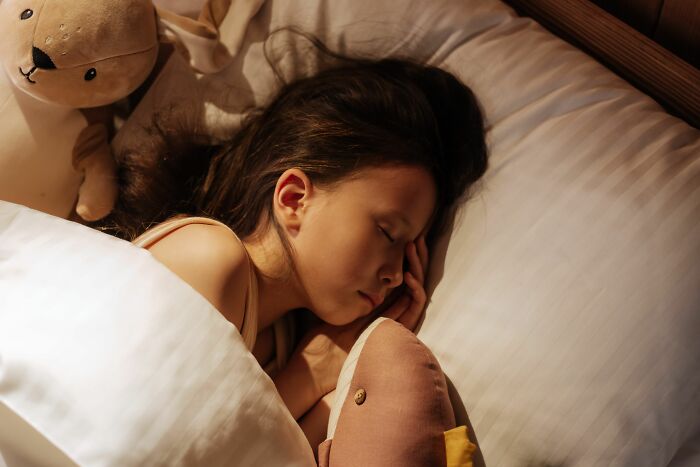 A girl sleeps peacefully in bed surrounded by stuffed animals, illustrating parents terrified of their own children.