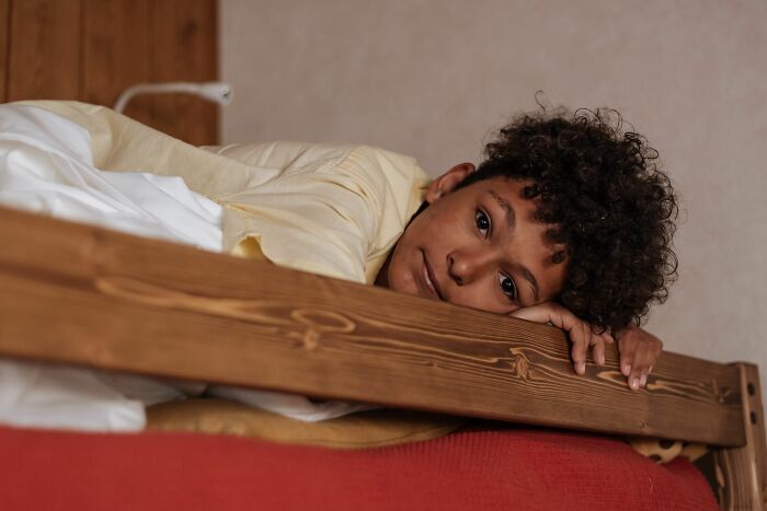 A child lying in bed, looking towards the camera, suggesting a moment that could make parents terrified.