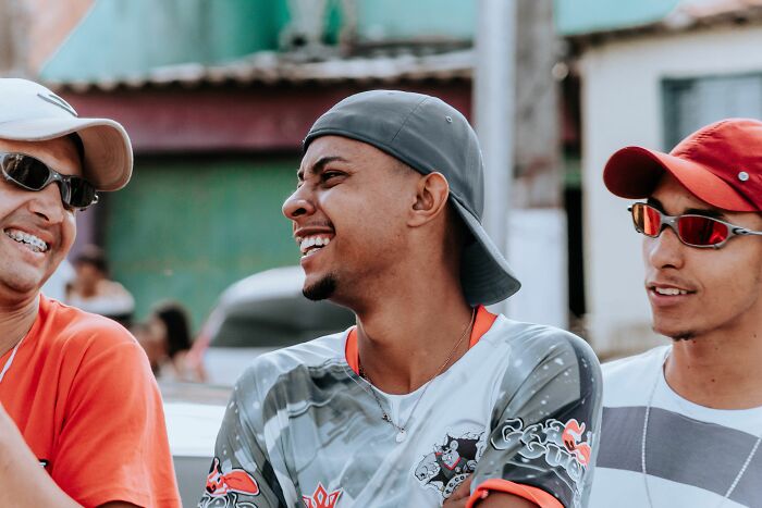 Three smiling young men talking outdoors, highlighting potential misunderstandings between locals and foreigners.