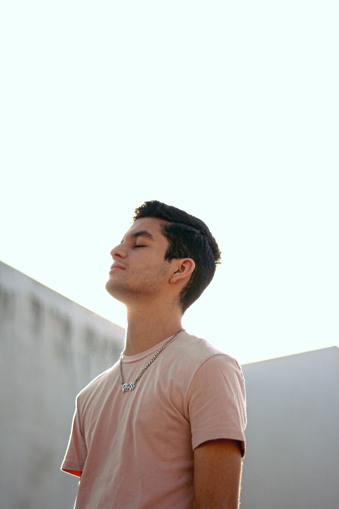 A man with closed eyes and a relaxed expression, possibly dealing with HR problems, against a bright sky.