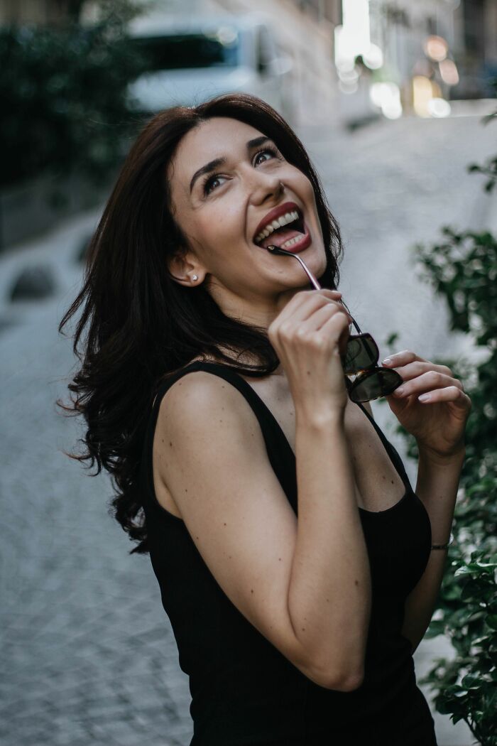A joyful woman bites her sunglasses, experiencing an unexpected twist that changed her life for the better.