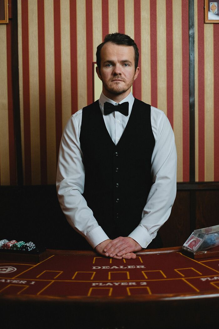 A casino dealer standing at a table, perhaps having a memorable final day at work or an interesting office story.