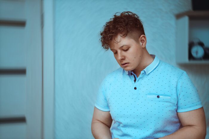 A man in a light blue polo shirt looks down thoughtfully, contemplating unexpected twists and turns that changed his life.