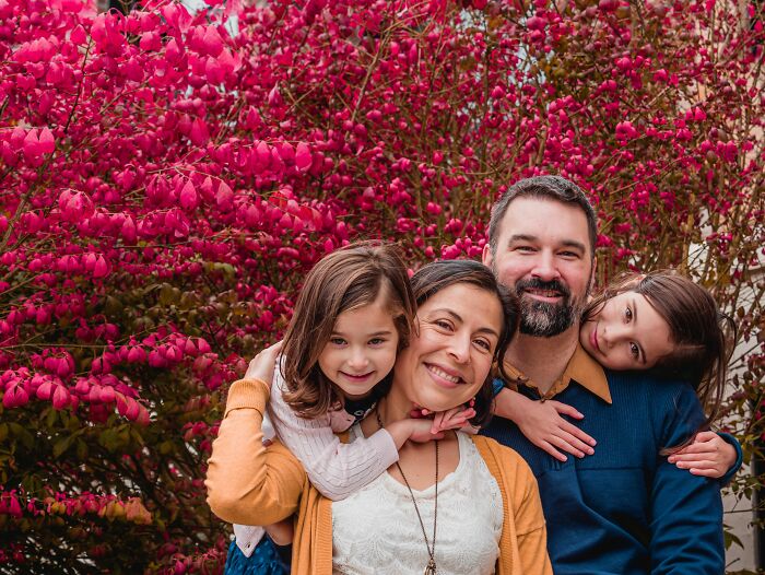 A happy family of four smiling at the camera, showing how twists and turns changed people's lives positively.