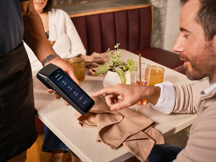 A customer pointing at a payment terminal, demonstrating American habits regarding tipping.