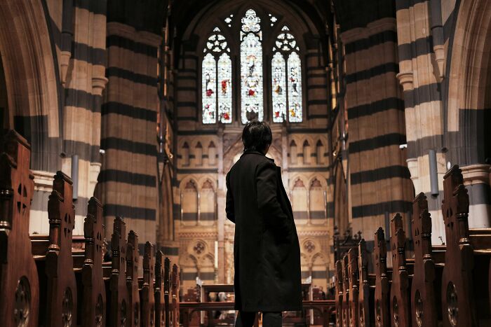 A person standing in a large church, contemplating subtle signs someone isn't as nice as they pretend to be.